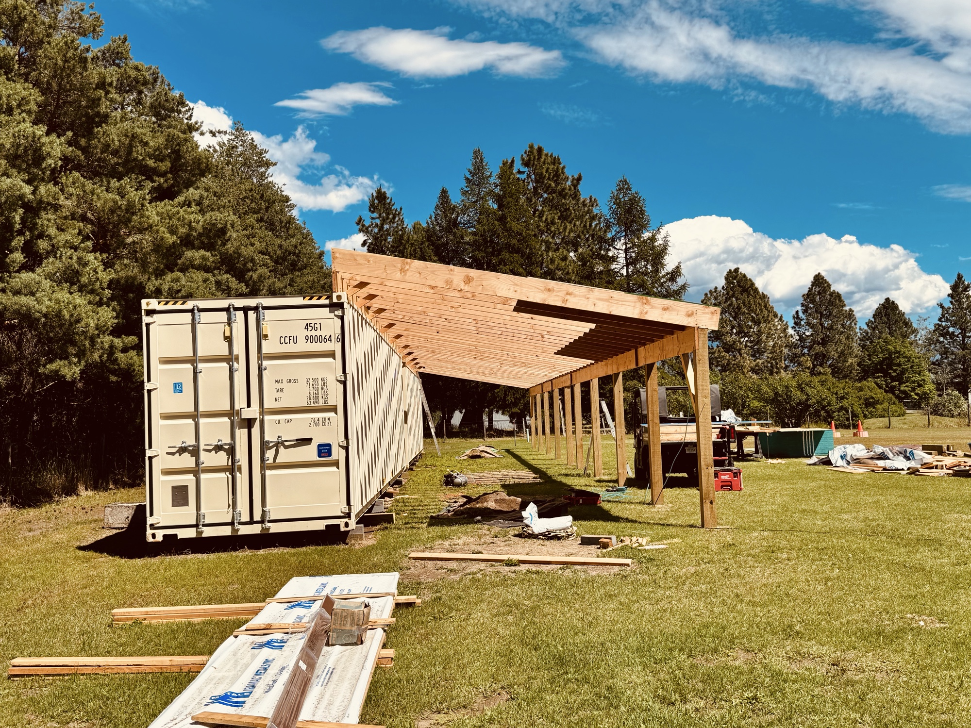 Large container row with timber-framed roof overhang under a blue sky