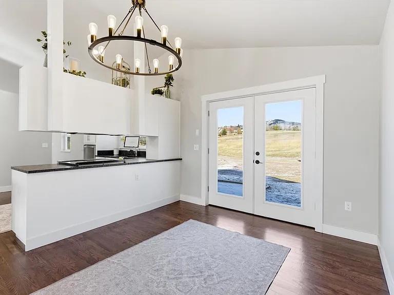 New construction dining area with round chandelier and French door access to outdoors
